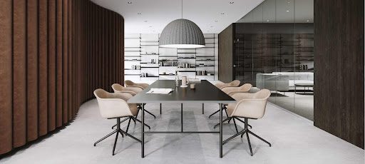 Modern conference room with a black table, six beige chairs, a large grey dome light fixture, glass wall, white shelves, and brown curtain.